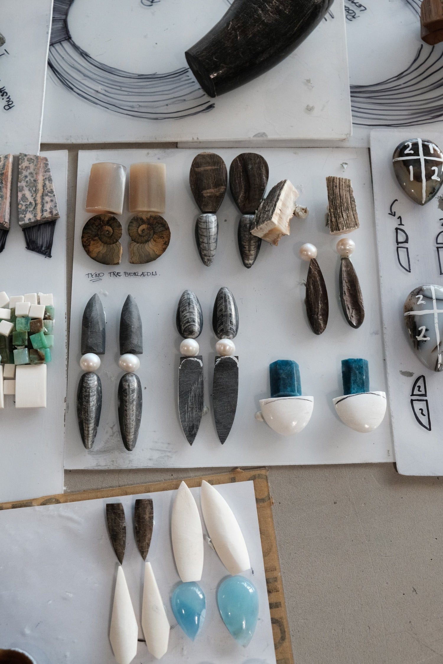 Earrings in horn, fossils, pearl and stone on studio boards