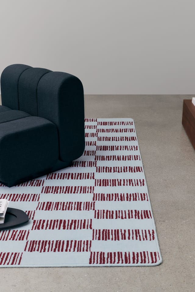 A pale blue and red patterned rug under a sofa