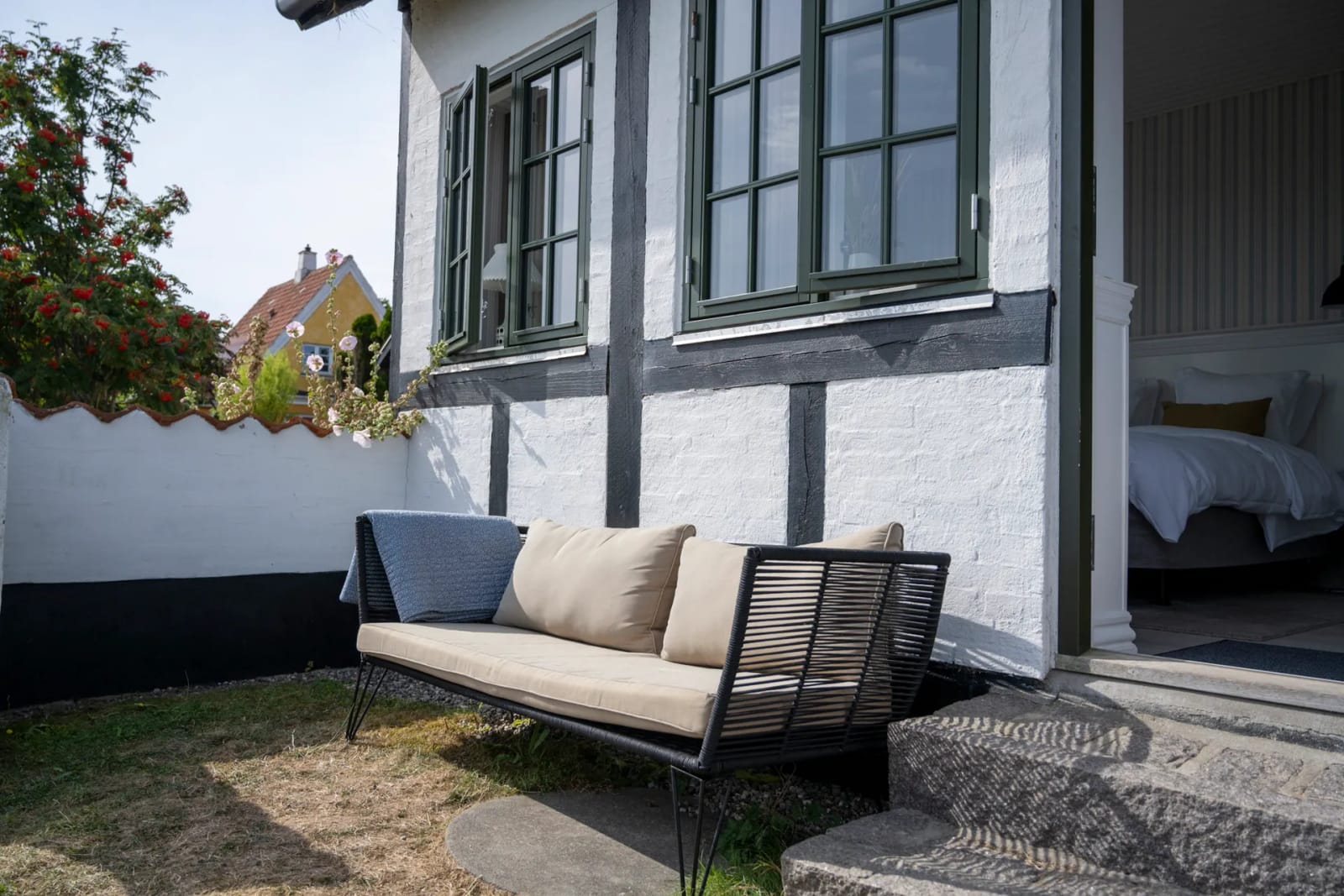 The whitewashed half-timbered house, with a room open to the garden