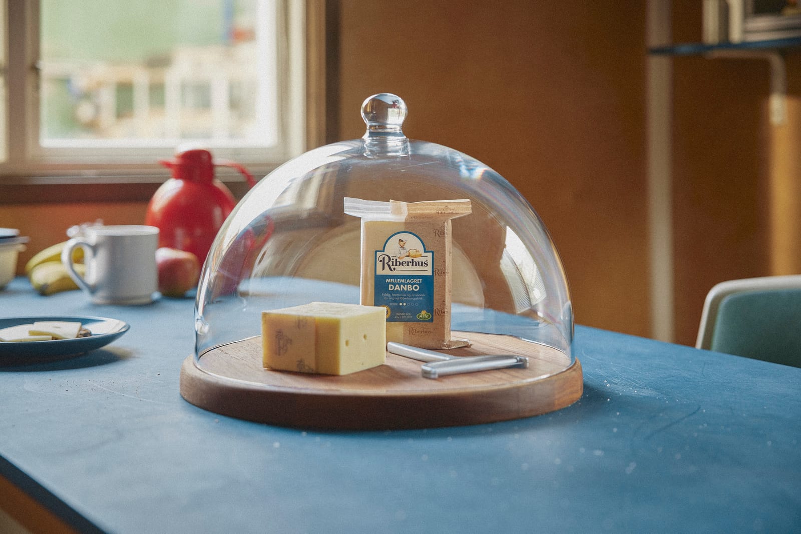 A piece of Riberhus Danbo under a glass cheese dome