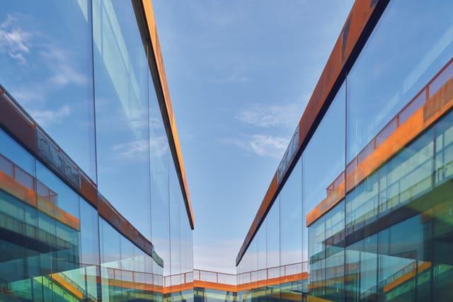 Glass facades and weathering-steel edges around the central square