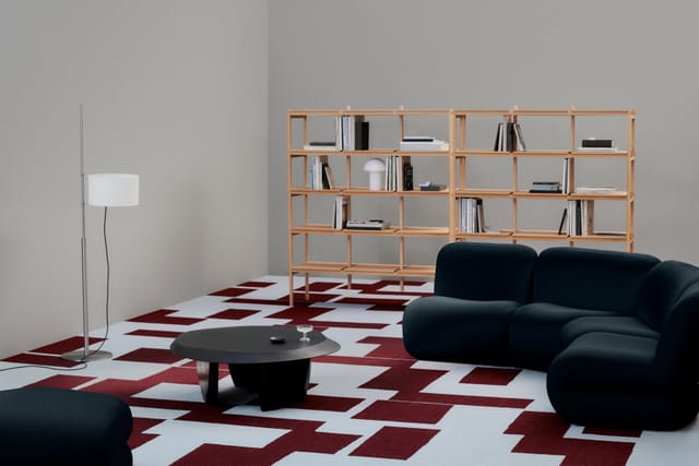A SHE carpet in red and white under a dark sofa