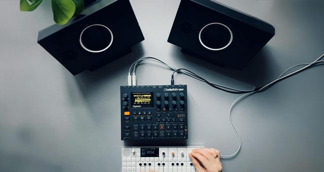 Two UNIT-4 speakers in black on a desk with synthesizers