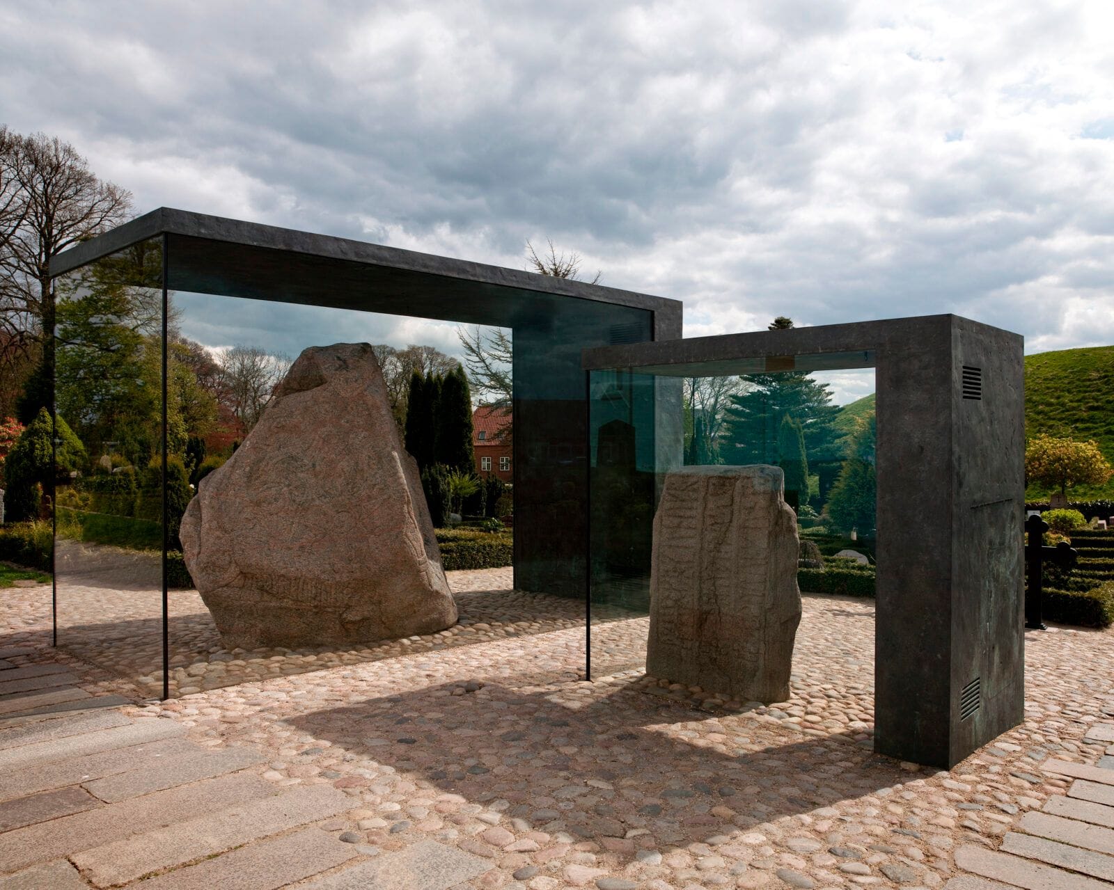 The two Jelling stones in their glass cases, with a mound behind