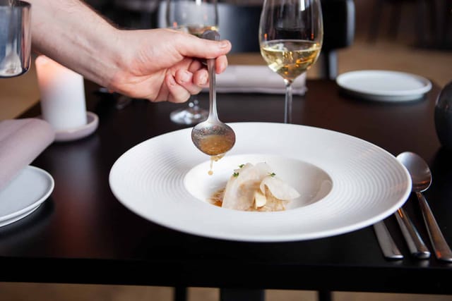 A sauce spooned over a course at the table