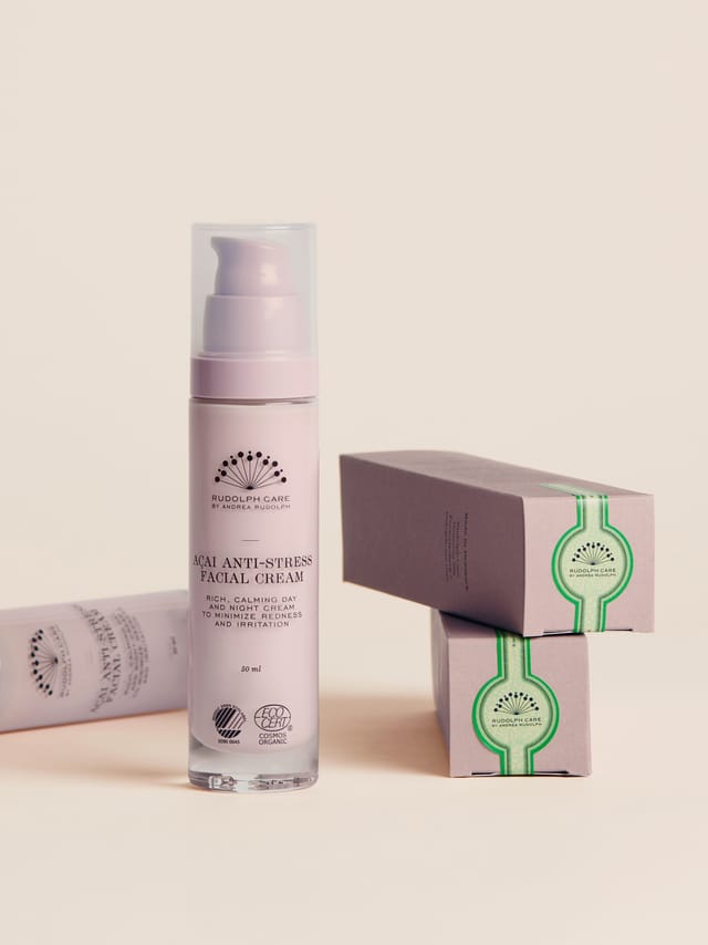 The cream's bottle beside its lilac and green boxes