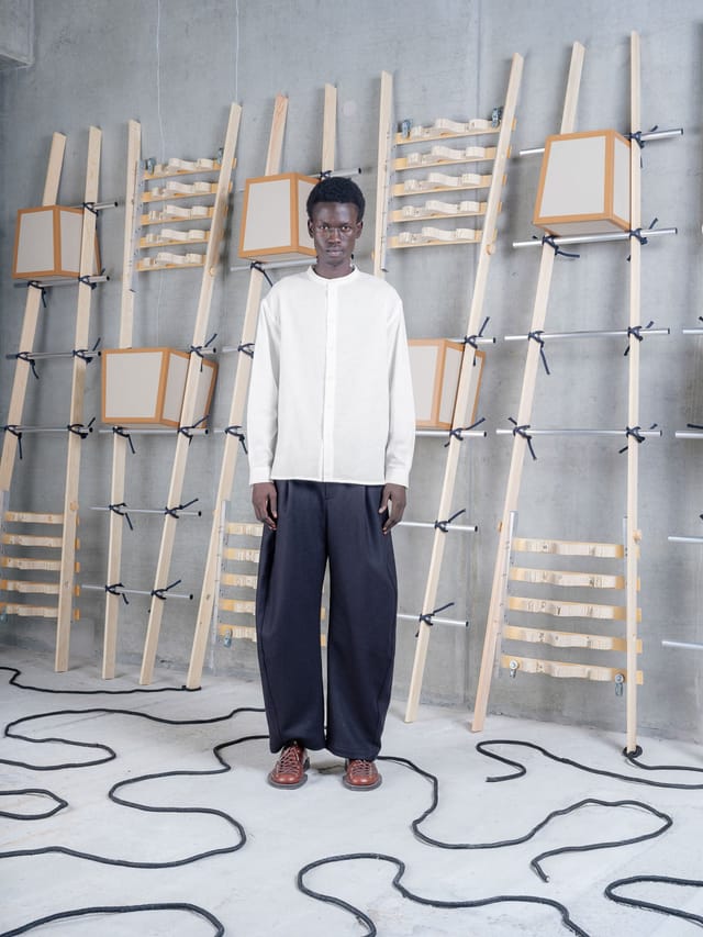 A collarless ecru shirt and wide navy trousers