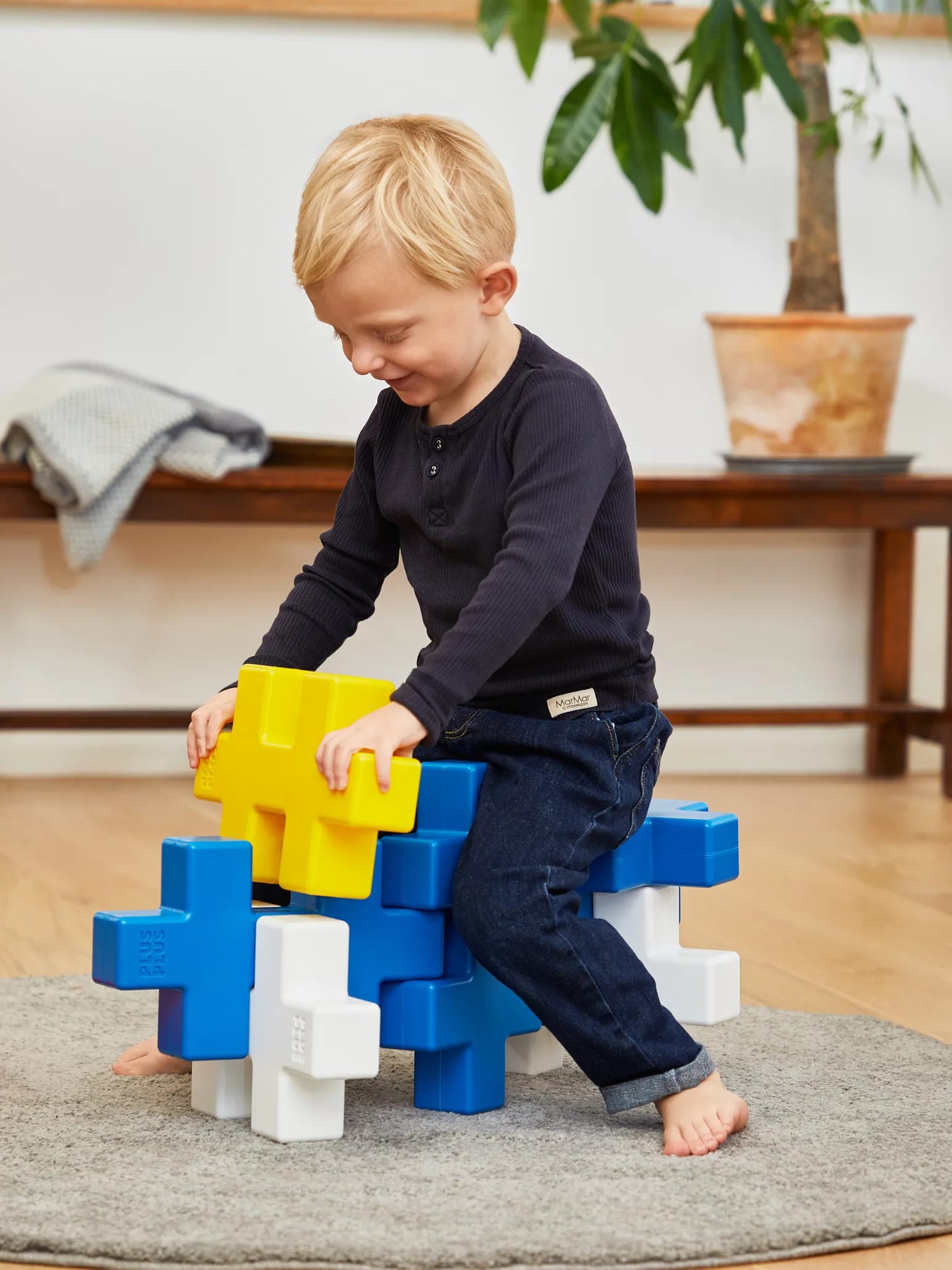 A child building on a seat made of KÆMPE pieces