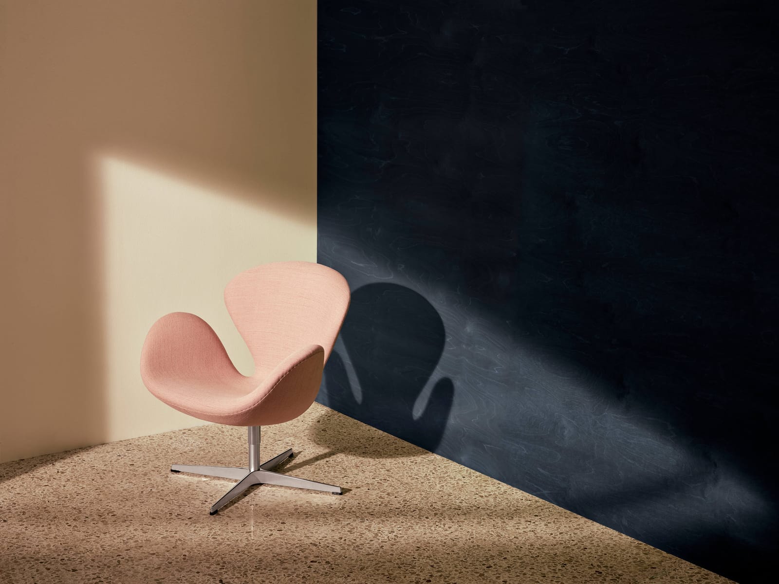 A Swan chair in pale pink fabric in the corner of a room