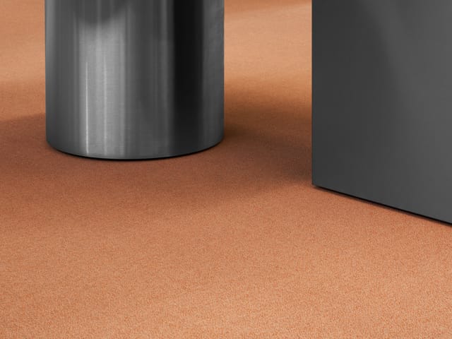 A terracotta MATTER carpet under a steel and dark table