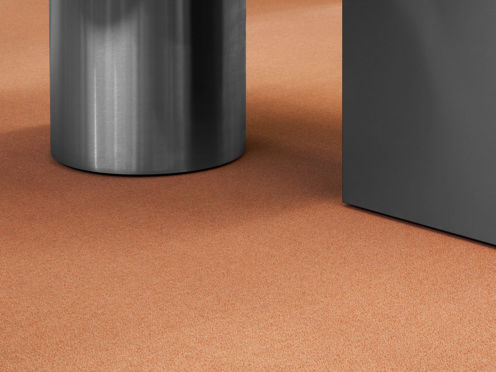 A terracotta MATTER carpet under a steel and dark table