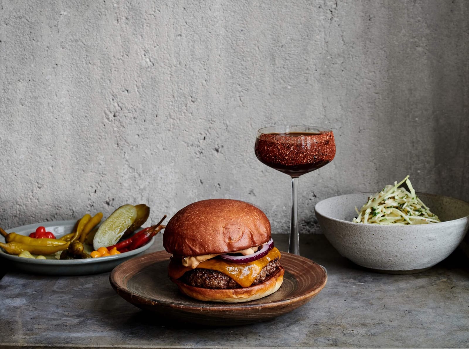 A cheeseburger with pickles and a cocktail