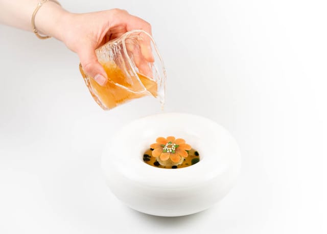 A broth poured at the table over a vegetable flower