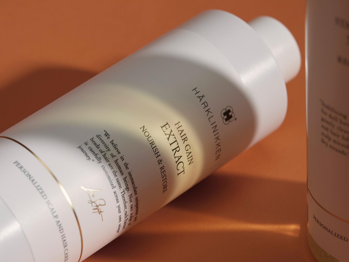 A bottle of Hair Gain Extract lying on an orange surface