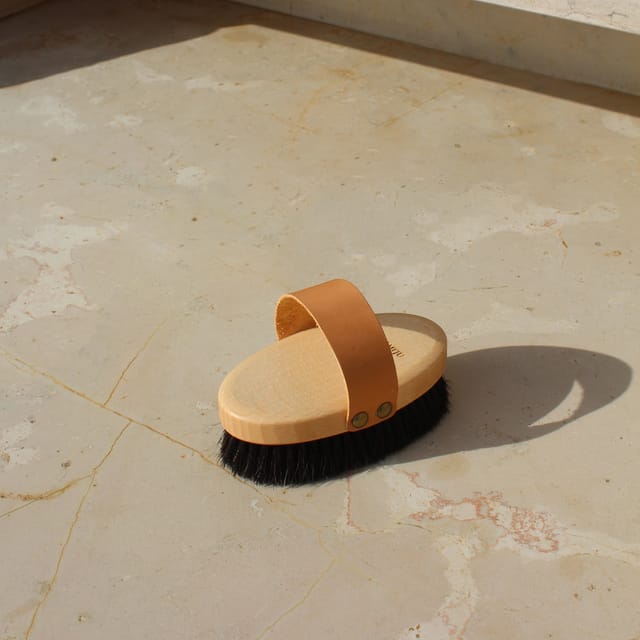 RECHARGE brush with dark bristles and leather strap on stone