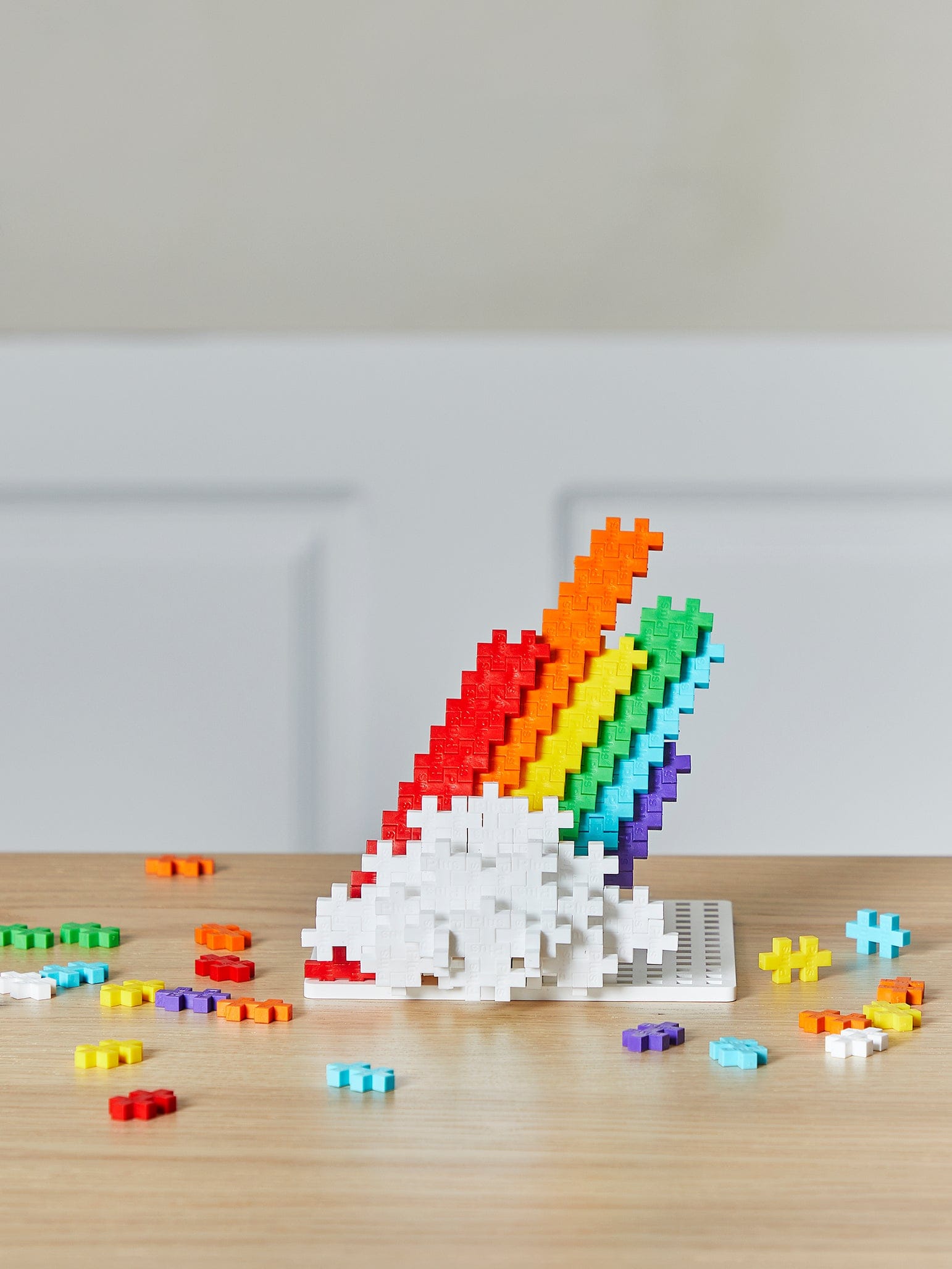 A rainbow and cloud built from Plus-Plus pieces on a table