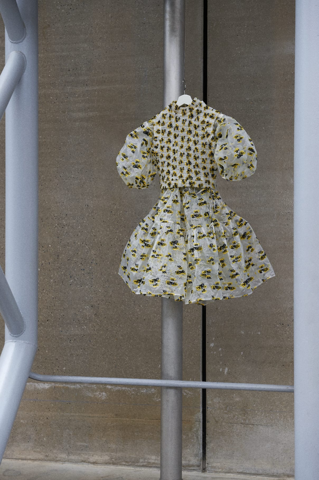 An Encore dress in yellow and black embroidered organza on a hanger