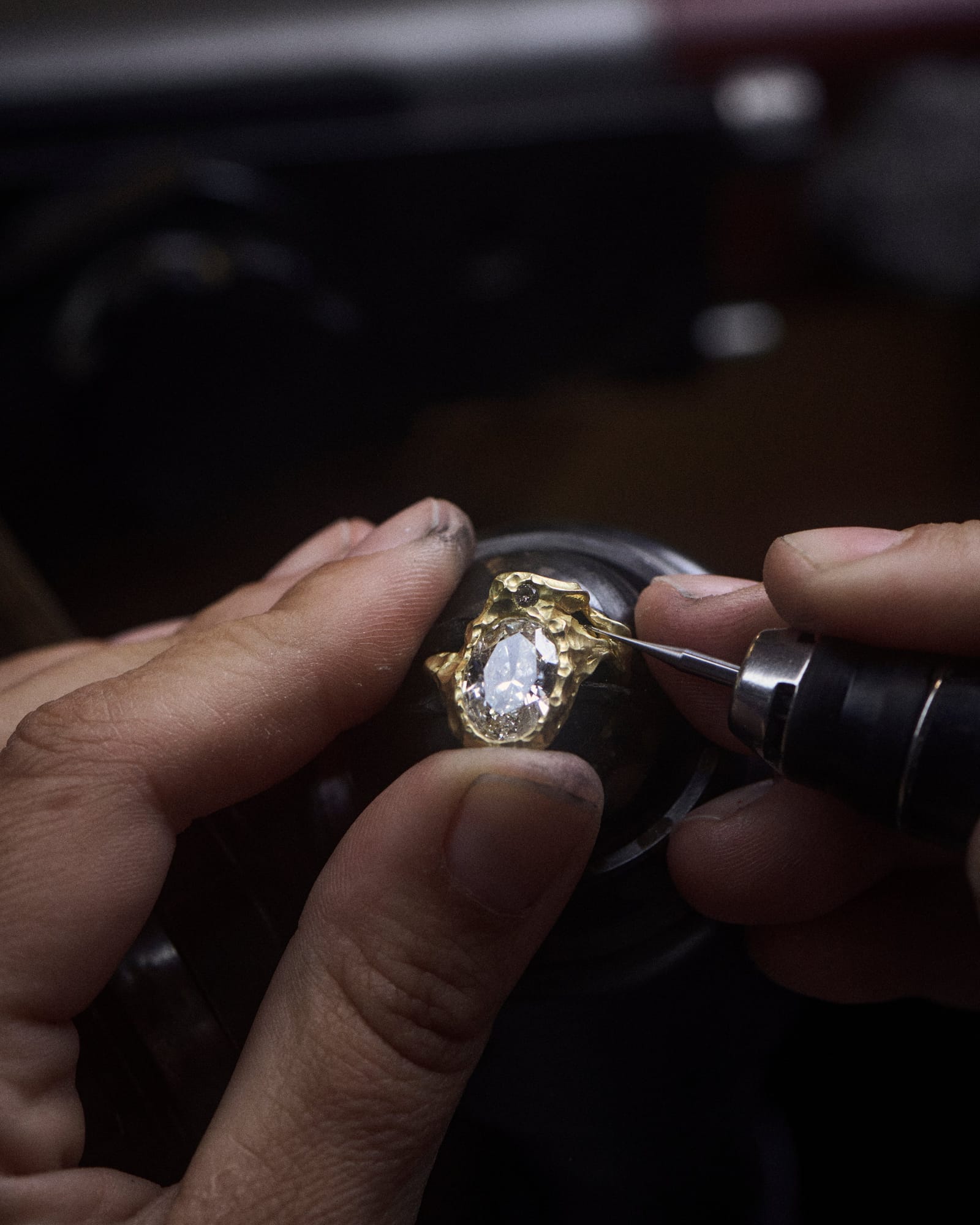 A diamond being set in a textured gold ring at the workbench