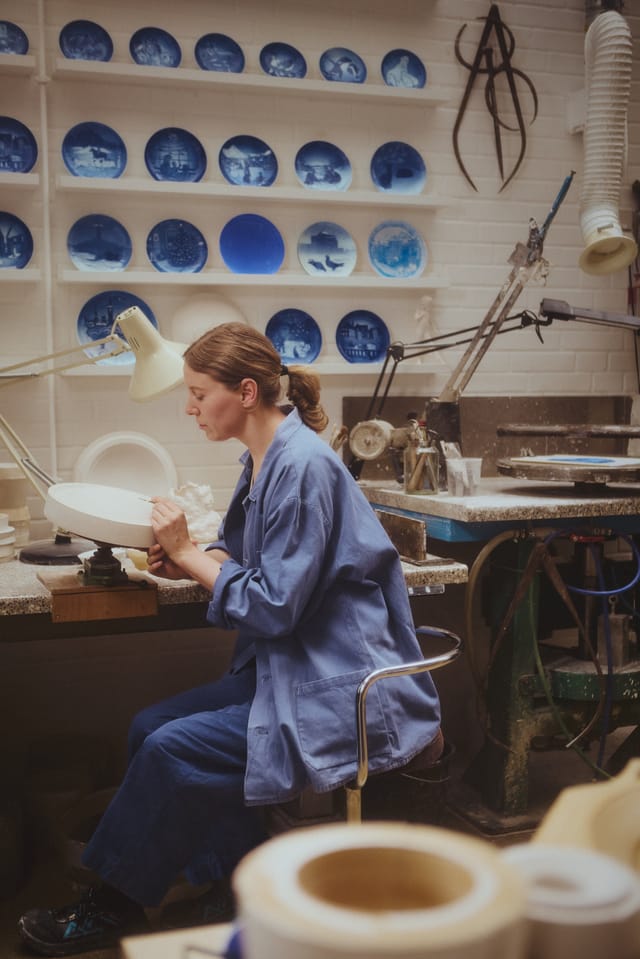 Work on a Christmas plate in the workshop, past plates on the wall