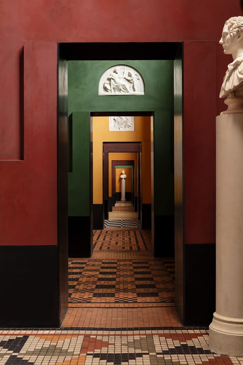 A row of painted galleries with mosaic floors and a marble bust