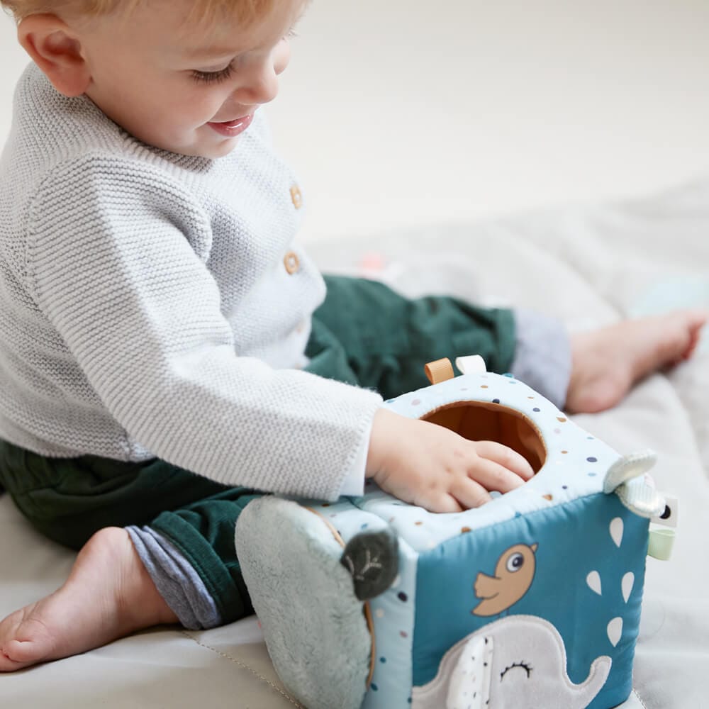 A toddler playing with a Done by Deer soft activity cube