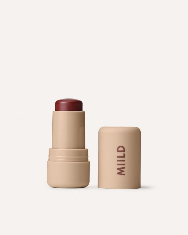 The balm stick in Deep Fig, cap beside it