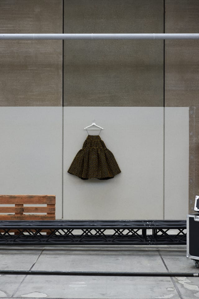 A black and gold Encore dress hung against a wall