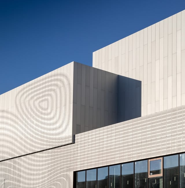 The perforated white facade of the 2017 building