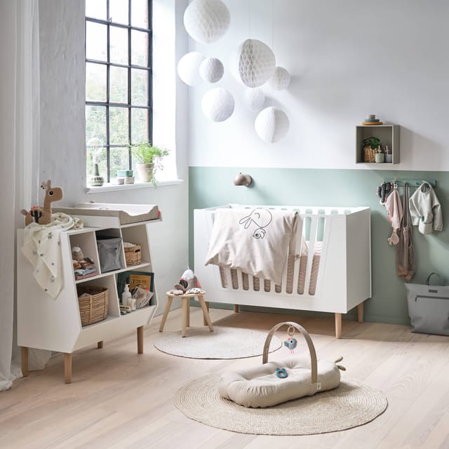 A nursery with a Done by Deer play gym, soft toys and furniture