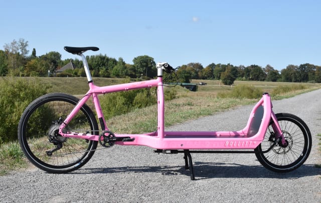 A pink Miss Bullitt cargo bike, side view