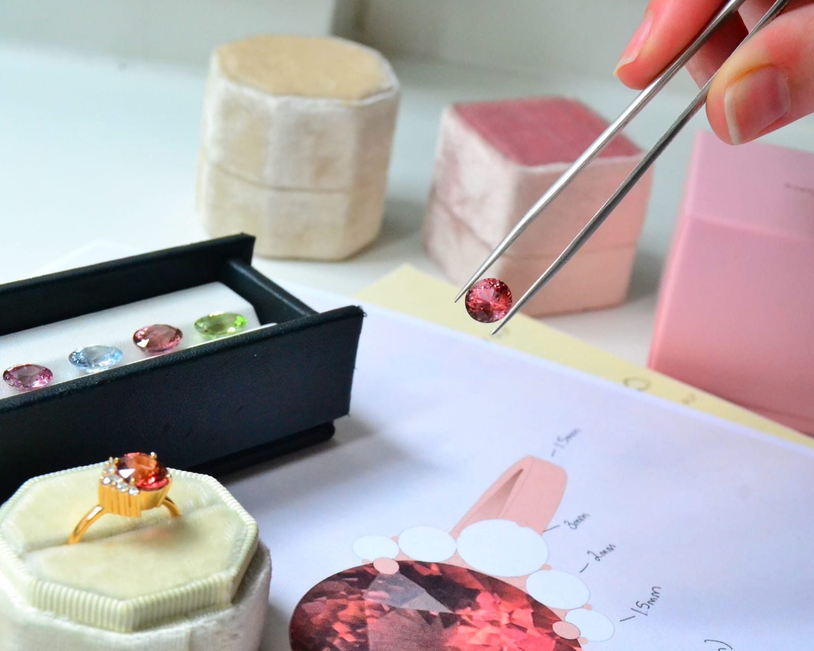 A gold ring, loose gemstones and a design sketch