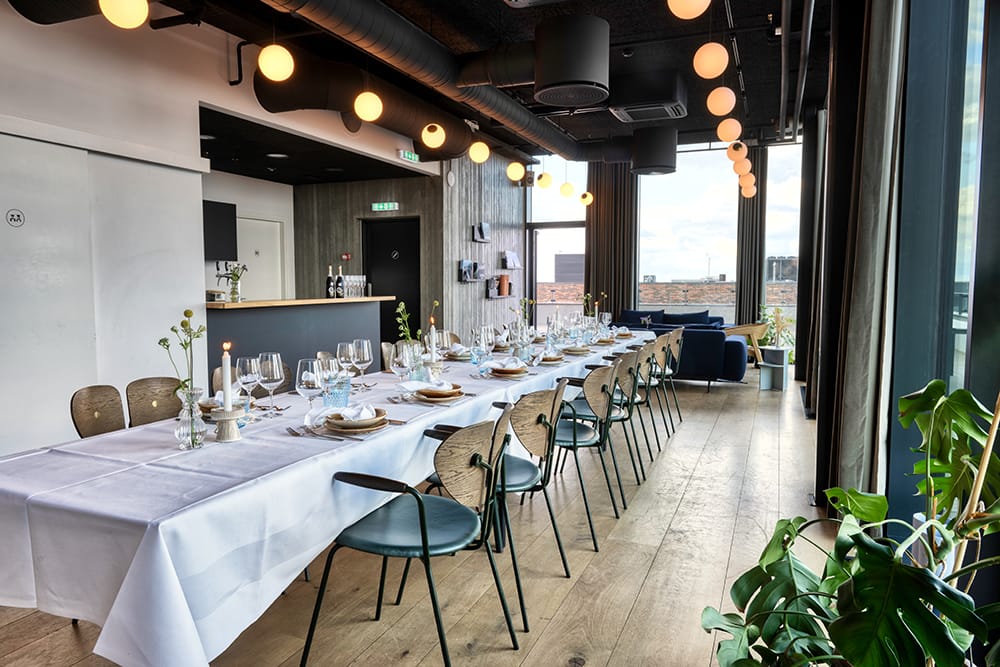 A long table laid by the windows at Aarhus Ø