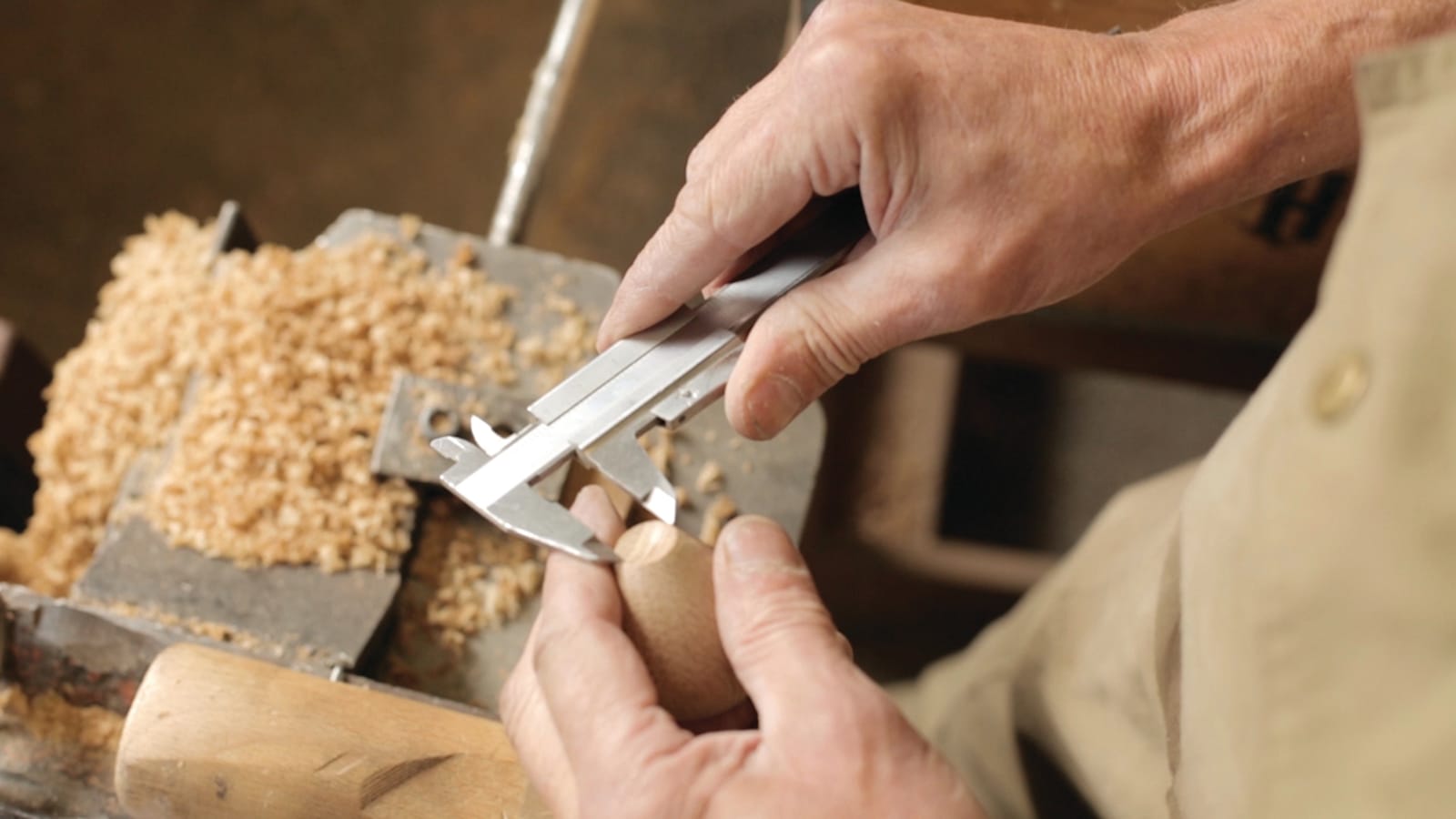 A wood turner measuring a turned piece